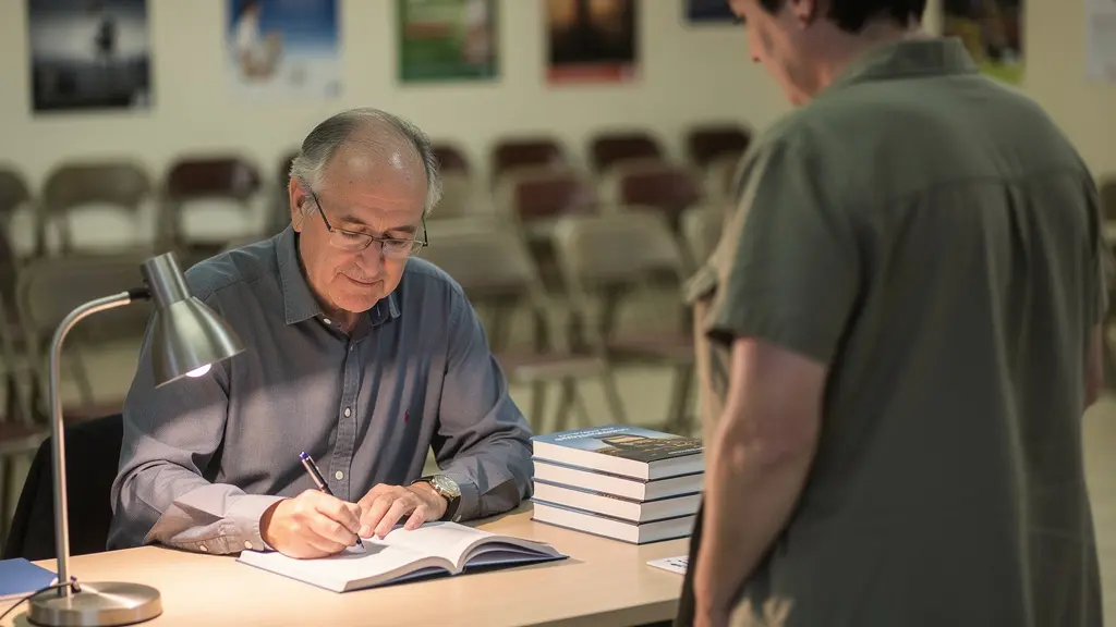 Auteur signant un livre pour un visiteur lors d'un salon littéraire de village